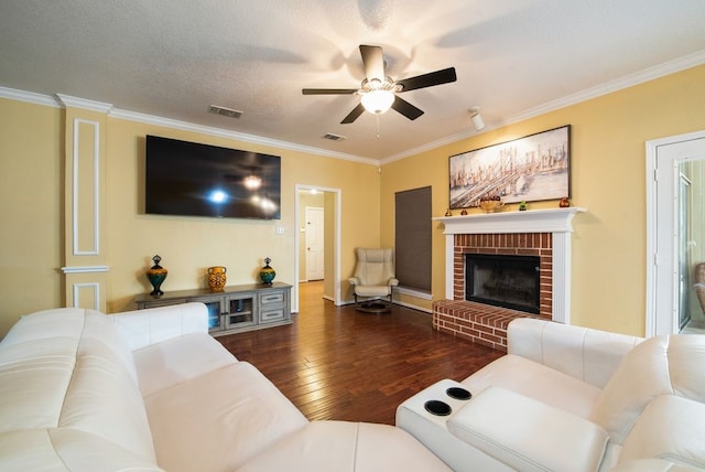 living room with hardwood / wood-style flooring, a fireplace, ornamental molding, and a textured ceiling