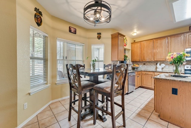 kitchen featuring light tile patterned floors, appliances with stainless steel finishes, light stone counters, and decorative backsplash