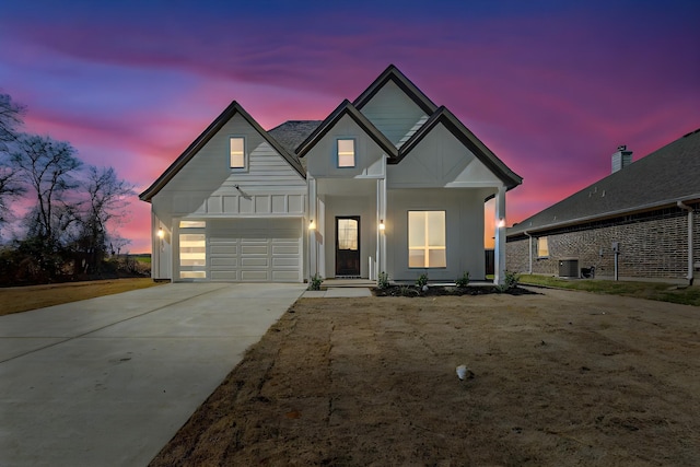 view of front of house featuring driveway, a garage, board and batten siding, covered porch, and central AC