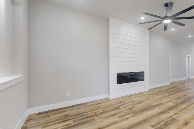 unfurnished living room featuring light wood-style flooring, a fireplace, baseboards, and recessed lighting