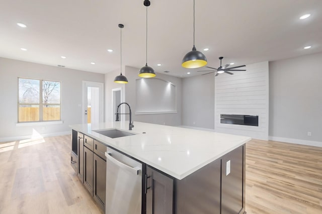 kitchen featuring recessed lighting, open floor plan, a large fireplace, a sink, and dishwasher