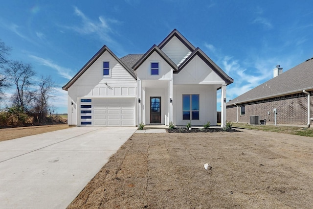 modern farmhouse with driveway, central AC unit, board and batten siding, and an attached garage