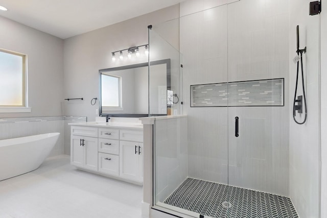 bathroom featuring a stall shower, wainscoting, a freestanding bath, and vanity