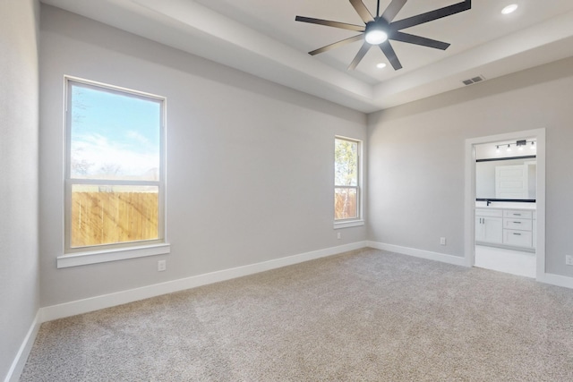 carpeted spare room with recessed lighting, a raised ceiling, visible vents, a ceiling fan, and baseboards