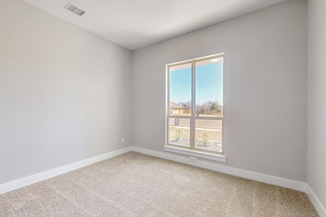 empty room with light colored carpet, visible vents, plenty of natural light, and baseboards