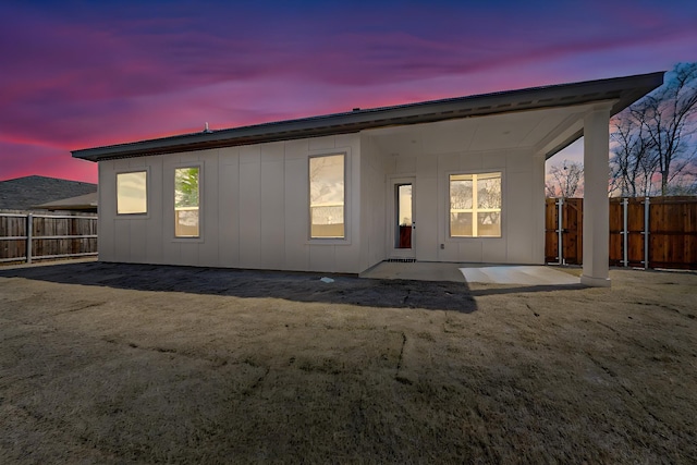 rear view of property featuring board and batten siding, fence, and a patio