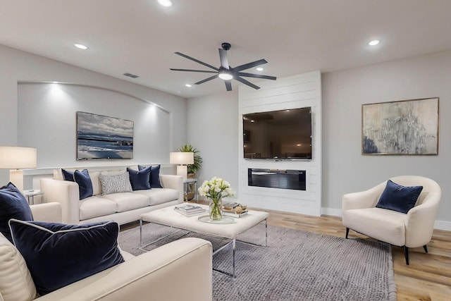 living area with a fireplace, light wood finished floors, recessed lighting, ceiling fan, and baseboards