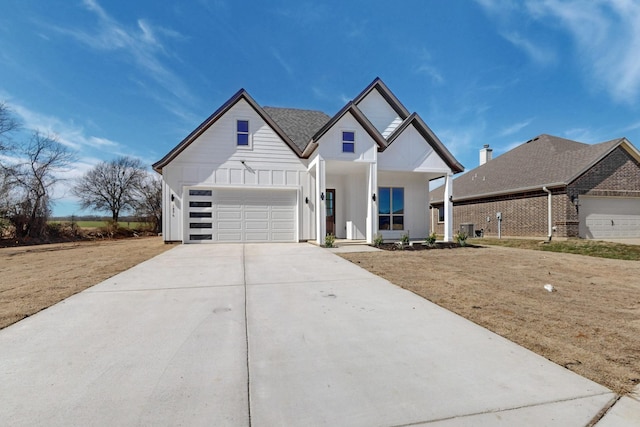 modern inspired farmhouse with board and batten siding, roof with shingles, driveway, and an attached garage