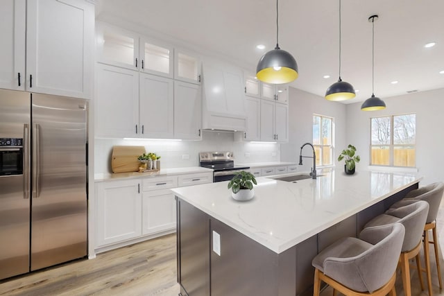 kitchen with white cabinets, a breakfast bar, a sink, stainless steel appliances, and backsplash