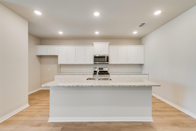 kitchen featuring stainless steel appliances, a sink, visible vents, and white cabinets