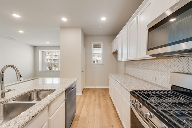 kitchen with plenty of natural light, light wood-style flooring, stainless steel appliances, and a sink