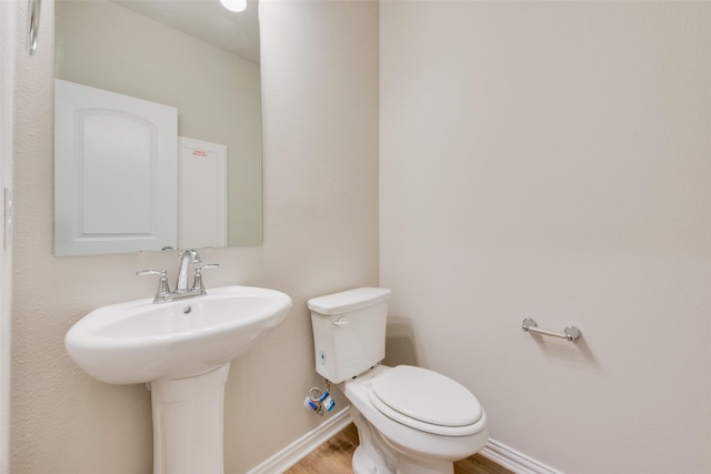 bathroom with a sink, wood finished floors, toilet, and baseboards