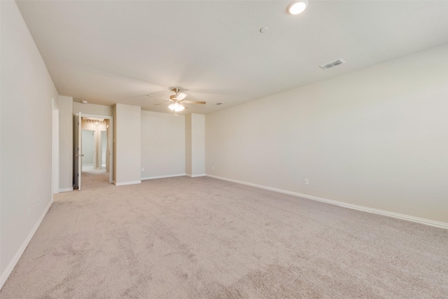 empty room featuring a ceiling fan, visible vents, light carpet, and baseboards