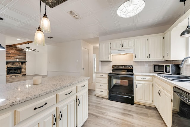 kitchen featuring under cabinet range hood, tasteful backsplash, black appliances, and a sink