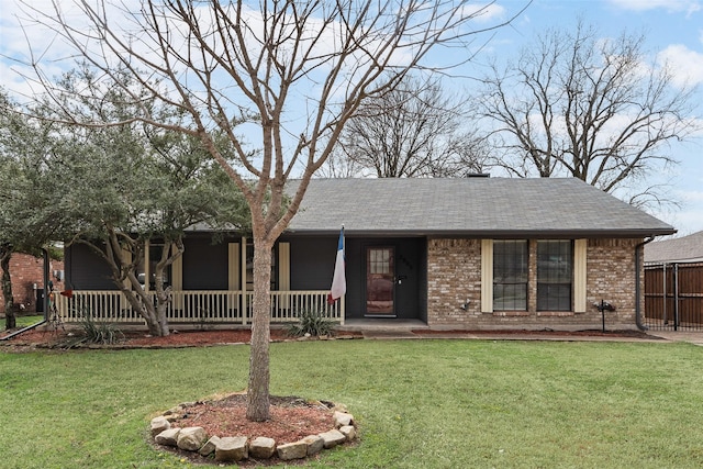 ranch-style home with brick siding, covered porch, a front yard, and roof with shingles