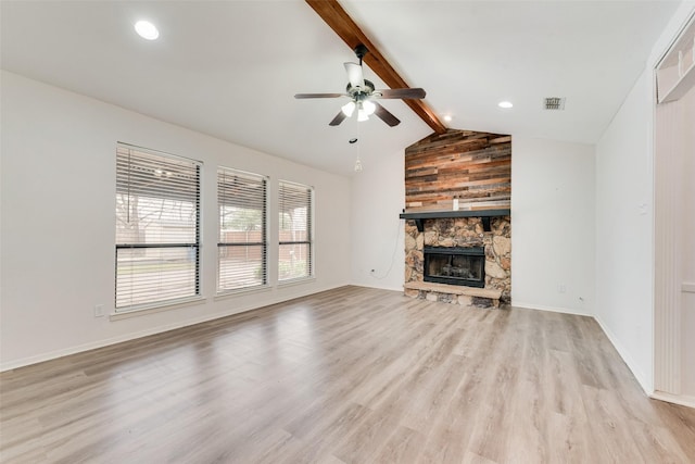 unfurnished living room with visible vents, lofted ceiling with beams, light wood-style floors, a stone fireplace, and ceiling fan