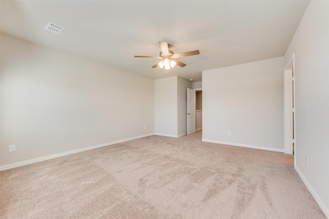 empty room with a ceiling fan, light colored carpet, visible vents, and baseboards