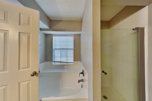 bathroom with a shower stall, a textured ceiling, and a bath