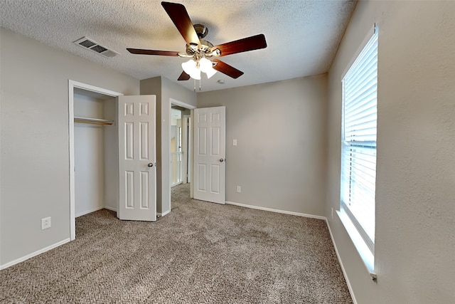 unfurnished bedroom with a textured ceiling, carpet floors, visible vents, and baseboards