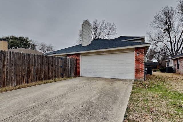 garage with concrete driveway and fence