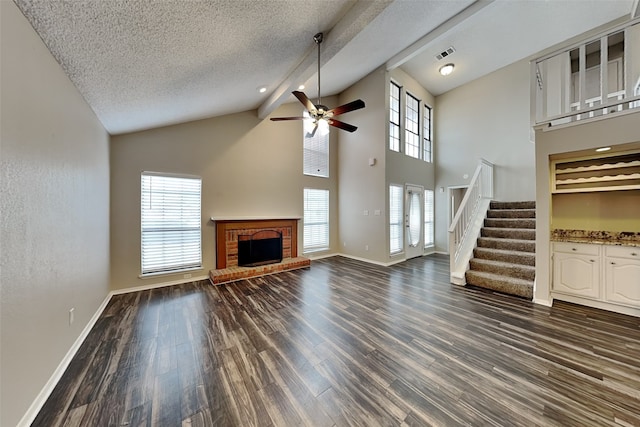 unfurnished living room with visible vents, dark wood-style floors, stairway, a textured ceiling, and a fireplace