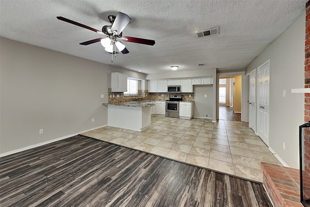 kitchen featuring visible vents, white cabinets, decorative backsplash, appliances with stainless steel finishes, and a peninsula