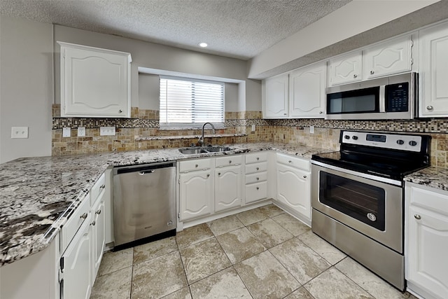 kitchen featuring decorative backsplash, light stone counters, stainless steel appliances, white cabinetry, and a sink