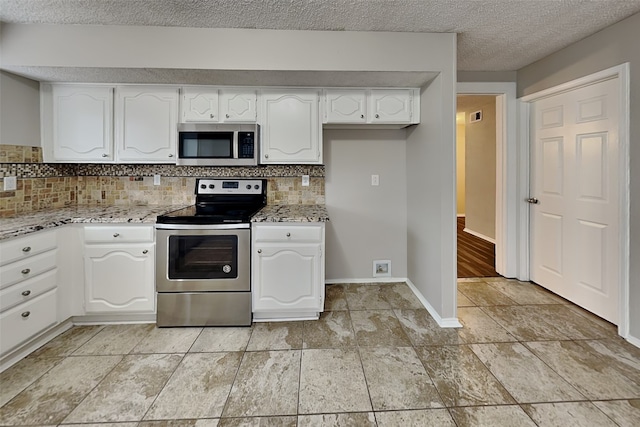 kitchen with appliances with stainless steel finishes, baseboards, white cabinetry, and decorative backsplash