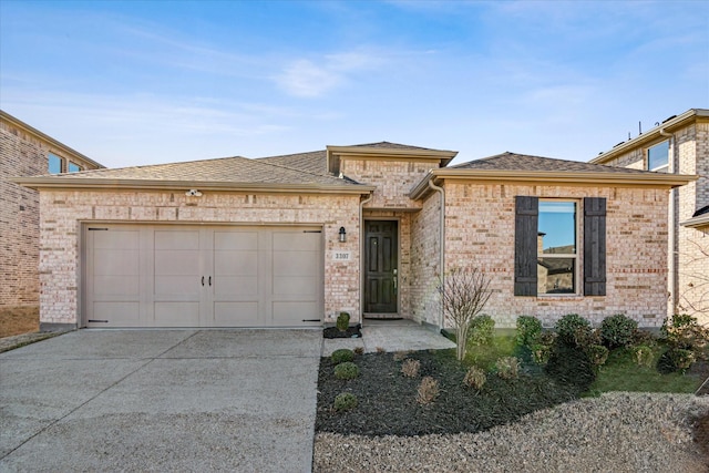 view of front of house with a garage, roof with shingles, driveway, and brick siding