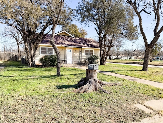 view of front of property with fence, a front lawn, and cooling unit