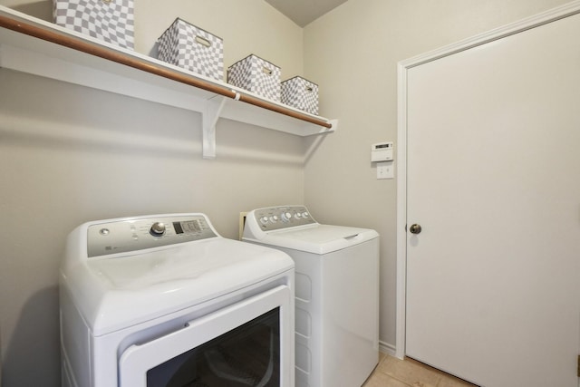 clothes washing area featuring laundry area, light tile patterned floors, and washer and clothes dryer