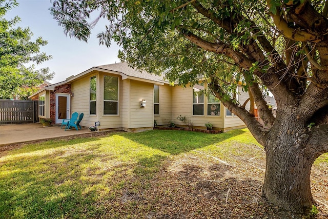 back of property with a yard, fence, and a patio