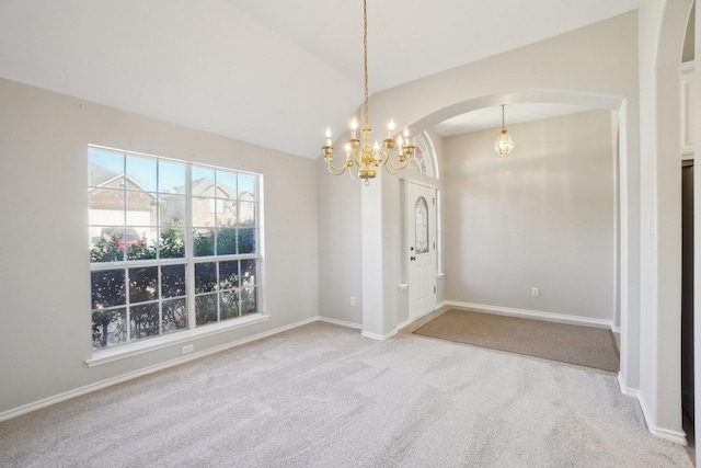 unfurnished room with baseboards, arched walkways, lofted ceiling, an inviting chandelier, and carpet