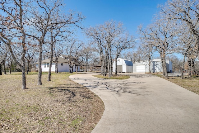 exterior space with a garage, an outbuilding, driveway, and a front yard