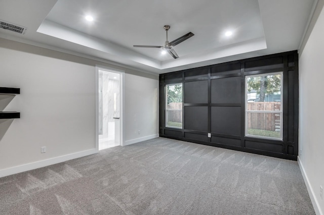 empty room featuring carpet, visible vents, and a tray ceiling