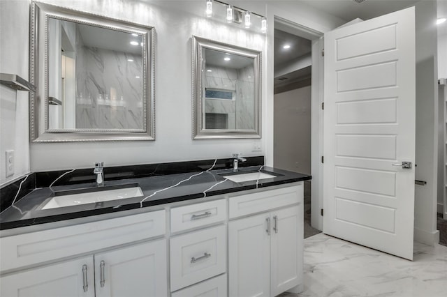 full bath featuring marble finish floor, a sink, a marble finish shower, and double vanity