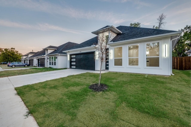 view of front of house with a garage, concrete driveway, roof with shingles, fence, and a front lawn