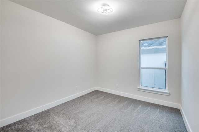 unfurnished room featuring dark carpet and baseboards