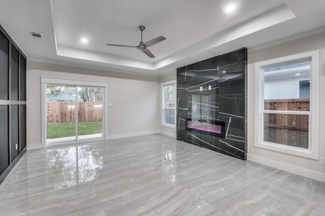 unfurnished living room with a tray ceiling, a healthy amount of sunlight, visible vents, and a fireplace