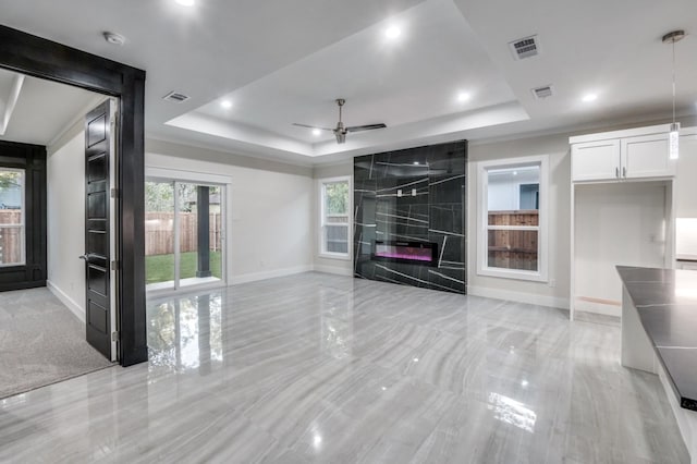 unfurnished living room featuring a tray ceiling, a fireplace, and visible vents