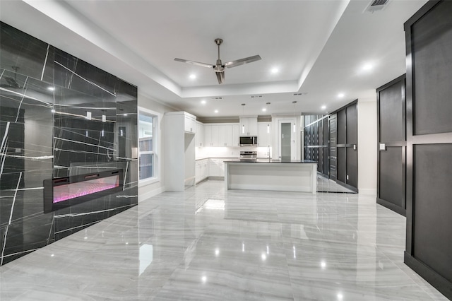 kitchen featuring visible vents, a raised ceiling, marble finish floor, stainless steel appliances, and a sink