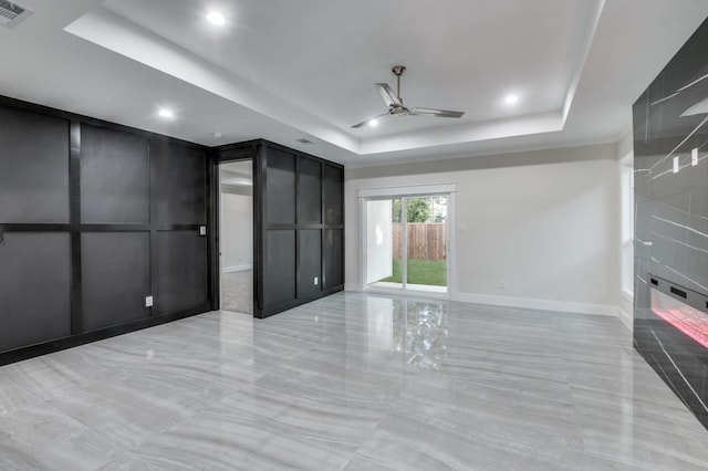 unfurnished room featuring visible vents, a ceiling fan, a tray ceiling, a decorative wall, and recessed lighting