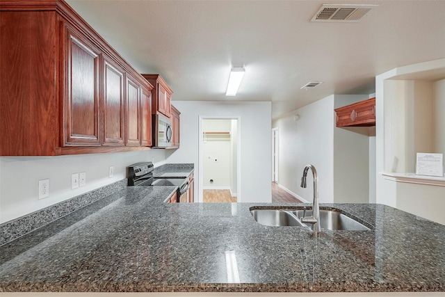 kitchen featuring dark stone countertops, visible vents, stainless steel appliances, and a sink