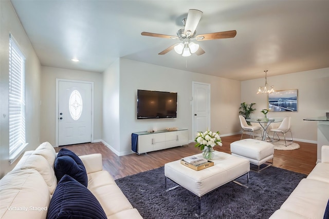 living room with baseboards, wood finished floors, and ceiling fan with notable chandelier