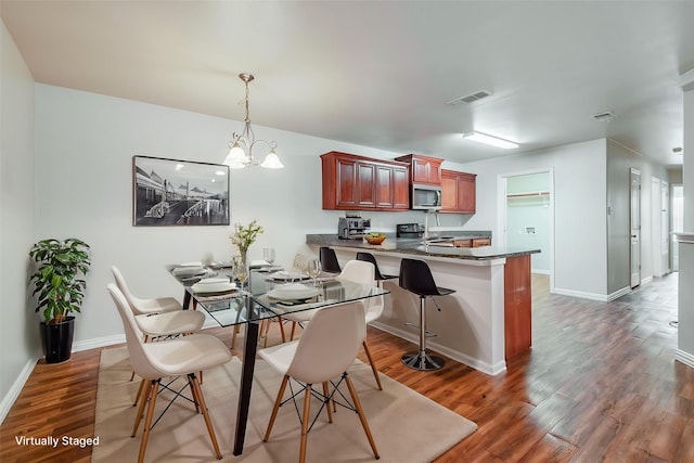 dining room with a chandelier, wood finished floors, visible vents, and baseboards