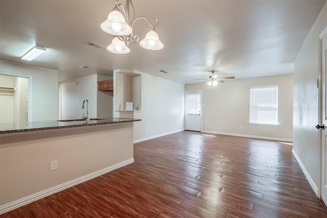 unfurnished living room featuring dark wood-type flooring, a ceiling fan, a sink, a textured ceiling, and baseboards