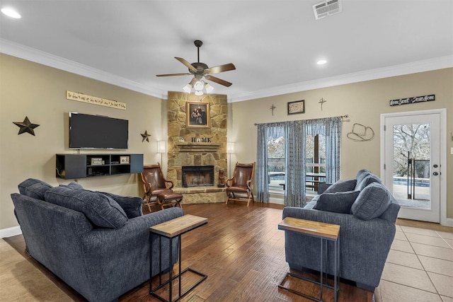 living area with a ceiling fan, a fireplace, visible vents, and crown molding