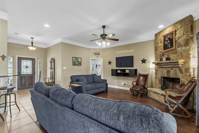 living room with a fireplace, ornamental molding, ceiling fan, wood finished floors, and baseboards