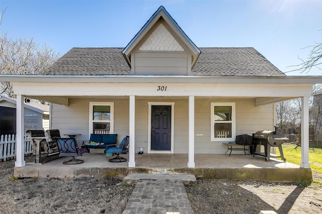 view of front of house with a shingled roof, fence, and a porch