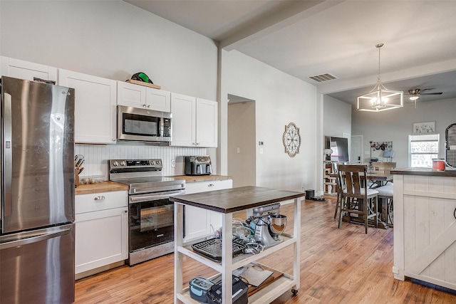 kitchen with visible vents, light wood-style flooring, appliances with stainless steel finishes, white cabinets, and beamed ceiling